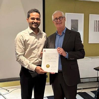 Ashik Abdul Kareem. An ISM graduate receives his certificate, which he seems very happy about. He is holding it along with an ISM's instructor.